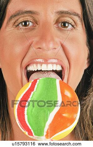 Stock Photograph - Female adult eating a lollipop. Fotosearch