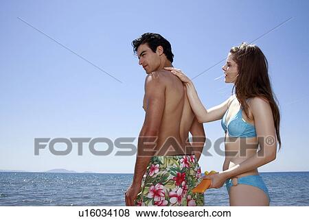 Female young adult applying suntan lotion on male's back View Large Photo Image Stock Photo - Female young adult applying suntan lotion on male's back. Fotosearch