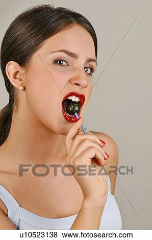 Stock Photo - Female young adult biting a lollipop. Fotosearch