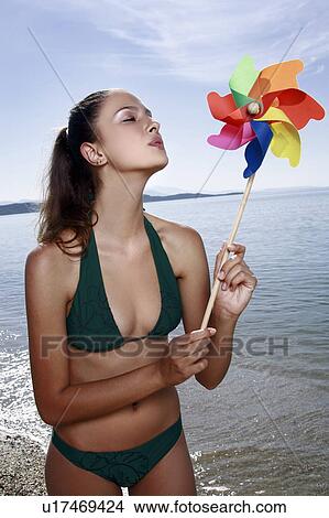 Picture - Female young adult blowing wind mobile on beach. Fotosearch
