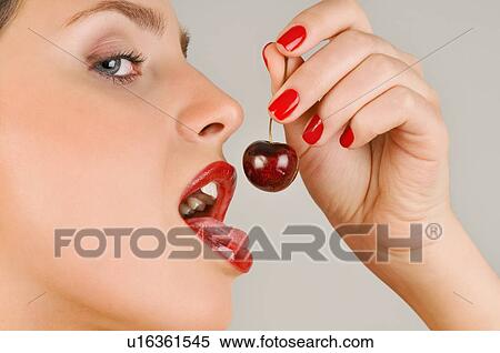 Stock Photography - Female young adult eating a cherry. Fotosearch