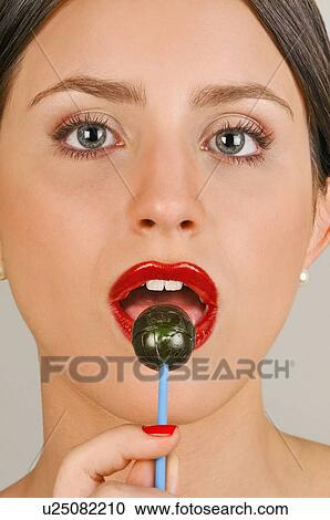 Stock Image - Female young adult eating a lollipop. Fotosearch