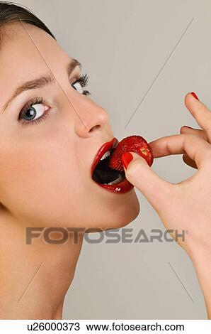 Stock Image - Female young adult eating a strawberry. Fotosearch