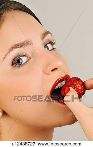 Stock Photo - Female young adult eating a strawberry. Fotosearch