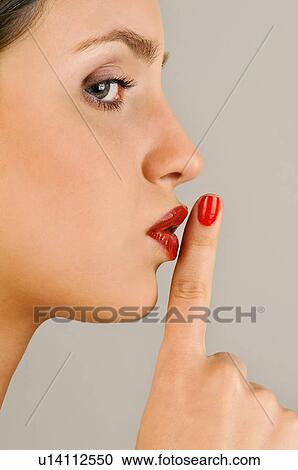 Stock Image - Female young adult; finger to lips. Fotosearch