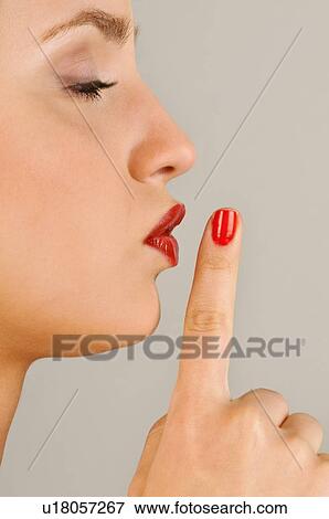 Stock Photo - Female young adult; finger to lips. Fotosearch