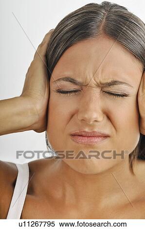 Stock Photography - Female young adult; hands holding ears; eyes closed. Fotosearch
