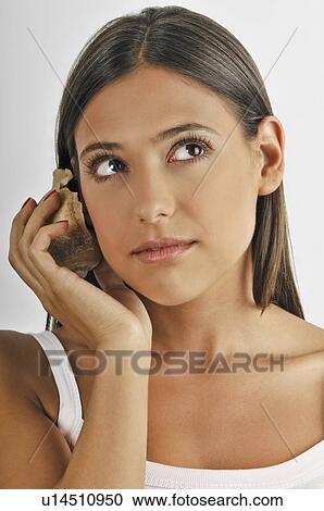 Female young adult; listening to seashell View Large Photo Image Stock Image - Female young adult; listening to seashell. Fotosearch