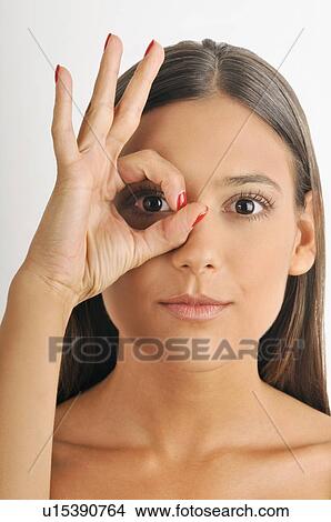 Picture - Female young adult; looking through fingers' hole. Fotosearch