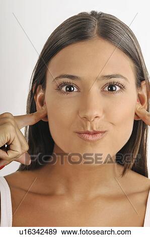 Stock Photo - Female young adult; plugging ears with fingers. Fotosearch