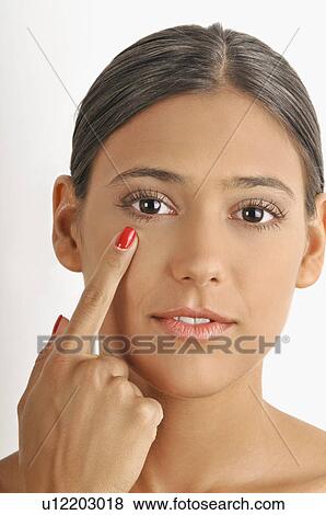 Stock Photo - Female young adult; pointing to eye. Fotosearch