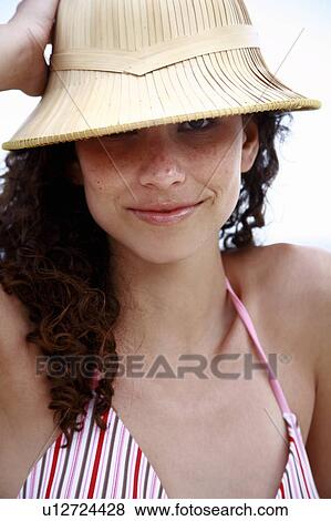 Stock Photo - Female young adult wearing sun hat on the beach. Fotosearch