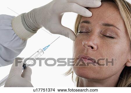 Hand holding botox syringe to woman's face View Large Photo Image Picture - Hand holding botox syringe to woman's face. Fotosearch