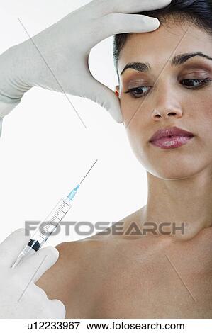 Hand holding botox syringe to young woman's face View Large Photo Image Stock Photo - Hand holding botox syringe to young woman's face. Fotosearch
