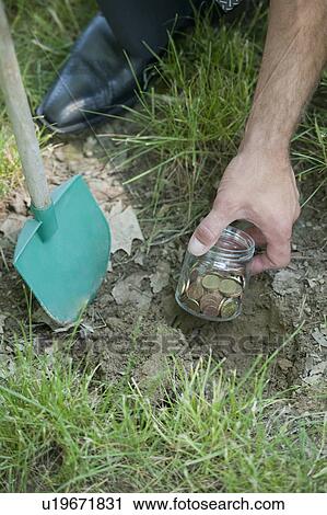 Hand with shovel hiding jar of coins in grass View Large Photo Image Stock Image - Hand with shovel hiding jar of coins in grass. Fotosearch
