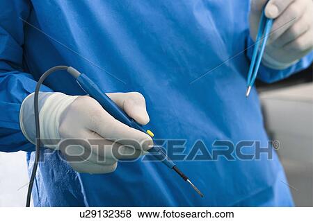 Hands holding electrical surgical scalpel and tweezers in operating room View Large Photo Image Stock Photo - Hands holding electrical surgical scalpel and tweezers in operating room. Fotosearch