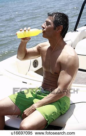 Stock Photography - Male adult on boat drinking juice. Fotosearch