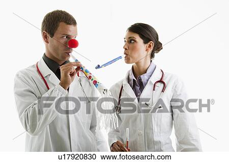 Stock Image - Male and female doctors with party toys. Fotosearch