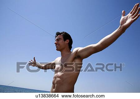 Picture - Male young adult on beach spreading arms. Fotosearch