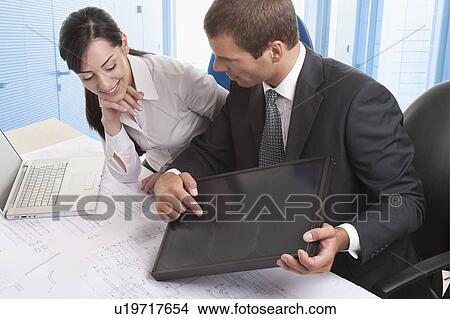 Man and woman at desk looking at solar panel View Large Photo Image Picture - Man and woman at desk looking at solar panel. Fotosearch