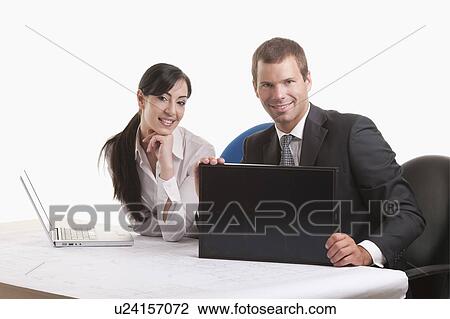 Stock Image - Man and woman at desk looking at solar panel. Fotosearch