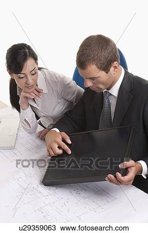 Stock Image - Man and woman at desk looking at solar panel. Fotosearch
