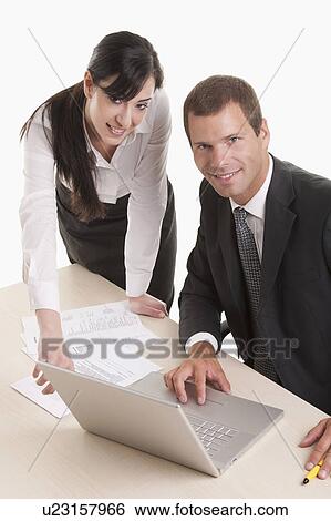 Man and woman at desk with documents and laptop View Large Photo Image Stock Photograph - Man and woman at desk with documents and laptop. Fotosearch