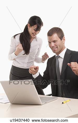 Man and woman at desk with laptop looking successful View Large Photo Image Stock Image - Man and woman at desk with laptop looking successful. Fotosearch
