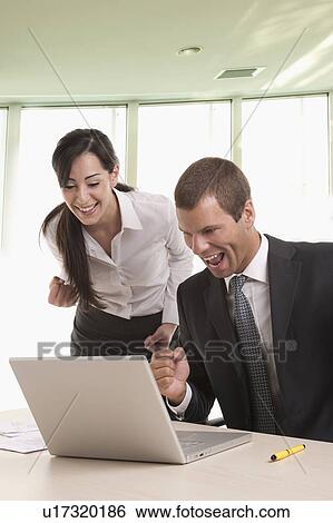 Man and woman at desk with laptop looking successful View Large Photo Image Stock Photograph - Man and woman at desk with laptop looking successful. Fotosearch