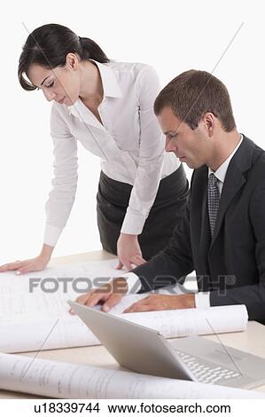 Man and woman looking over plans at desk View Large Photo Image Picture - Man and woman looking over plans at desk. Fotosearch