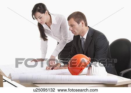 Man and woman looking over plans at desk View Large Photo Image Stock Image - Man and woman looking over plans at desk. Fotosearch