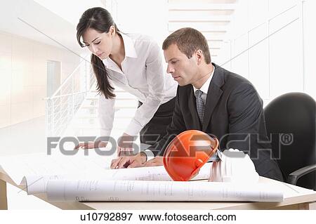 Man and woman looking over plans at desk View Large Photo Image Stock Photo - Man and woman looking over plans at desk. Fotosearch