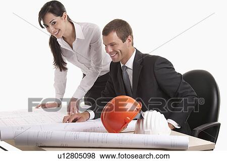 Stock Photo - Man and woman looking over plans at desk. Fotosearch