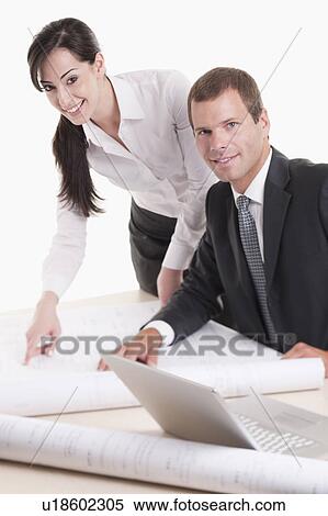 Stock Photography - Man and woman looking over plans at desk. Fotosearch