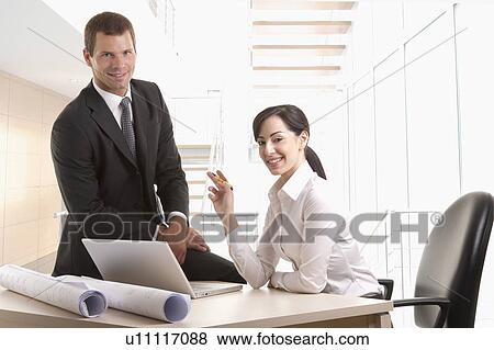 Man and woman with plans and laptop at desk View Large Photo Image Stock Photo - Man and woman with plans and laptop at desk. Fotosearch