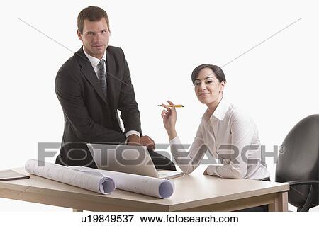 Man and woman with plans and laptop at desk View Large Photo Image Stock Photo - Man and woman with plans and laptop at desk. Fotosearch