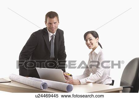 Man and woman with plans and laptop at desk View Large Photo Image Stock Photography - Man and woman with plans and laptop at desk. Fotosearch