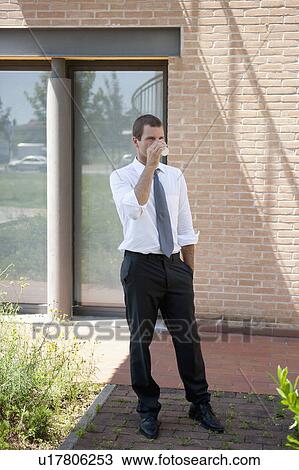 Man drinking from cup outside building View Large Photo Image Stock Image - Man drinking from cup outside building. Fotosearch