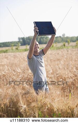 Man holding up solar panel in wheat field View Large Photo Image Stock Image - Man holding up solar panel in wheat field. Fotosearch