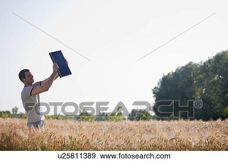 Man holding up solar panel in wheat field View Large Photo Image Stock Photo - Man holding up solar panel in wheat field. Fotosearch