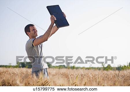 Man holding up solar panel in wheat field View Large Photo Image Stock Photography - Man holding up solar panel in wheat field. Fotosearch