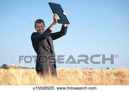 Man in suit holding up solar panel in wheat field View Large Photo Image Stock Image - Man in suit holding up solar panel in wheat field. Fotosearch