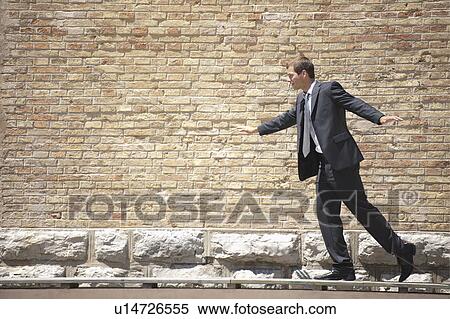 Stock Photography - Man in suit walking on ramp by wall. Fotosearch
