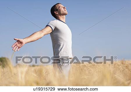 Man looking up with arms stretched out in wheat field View Large Photo Image Stock Photo - Man looking up with arms stretched out in wheat field. Fotosearch