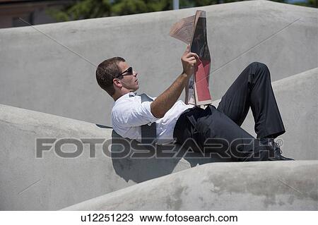 Man lying down on wall reading newspaper View Large Photo Image Stock Image - Man lying down on wall reading newspaper. Fotosearch