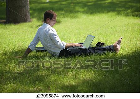 Man sitting in grass with laptop View Large Photo Image Picture - Man sitting in grass with laptop. Fotosearch