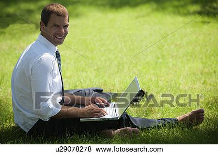 Man sitting in grass with laptop View Large Photo Image Stock Photo - Man sitting in grass with laptop. Fotosearch