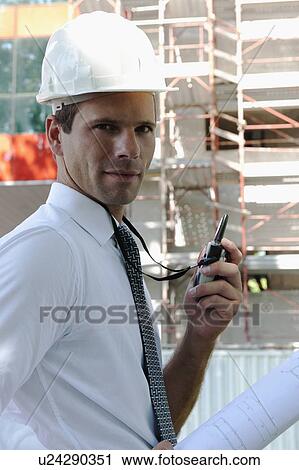 Stock Image - Man with hardhat and walky talky radio at construction site. Fotosearch
