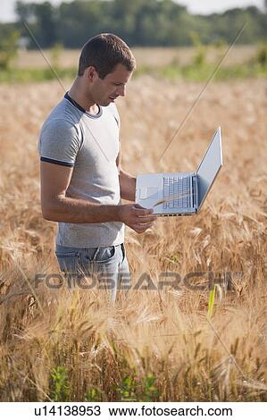 Stock Image - Man with laptop computer in wheat field. Fotosearch