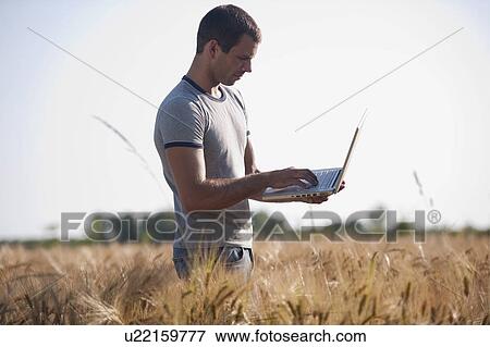 Stock Photo - Man with laptop computer in wheat field. Fotosearch